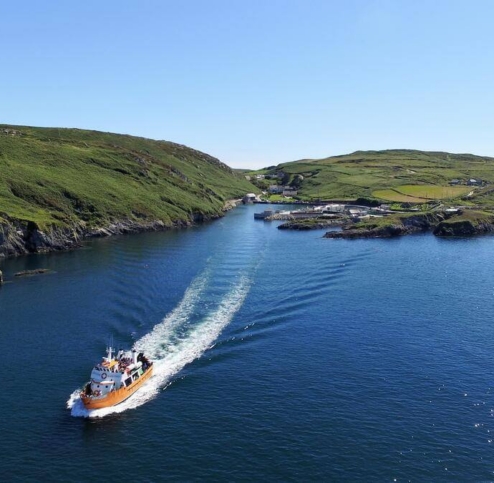 Scenic coastal view with a boat cruising through a calm bay under clear blue skies.