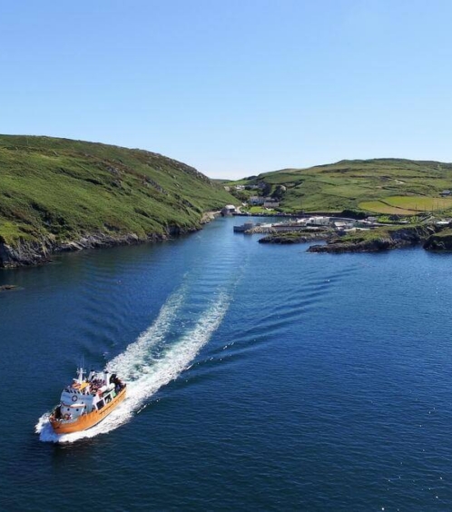 Scenic coastal view with a boat cruising through a calm bay under clear blue skies.