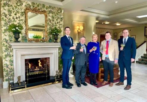 Group enjoying a warm welcome at Fernhill House Hotel lobby with a cosy fireplace.