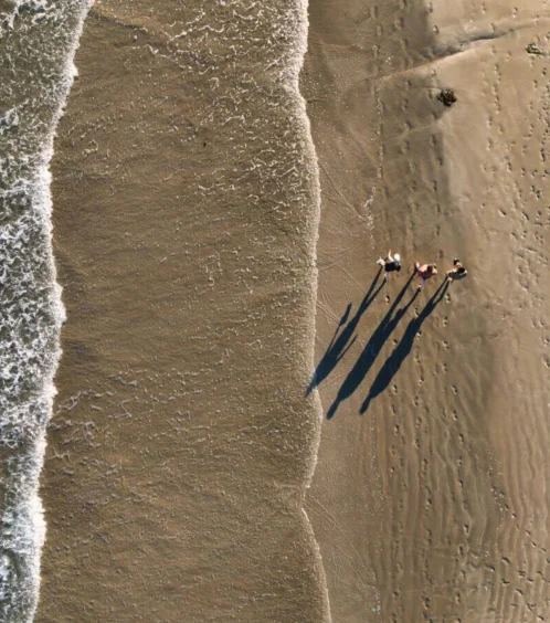 Family walking on a sandy beach near ocean waves at Fernhill House Hotel.