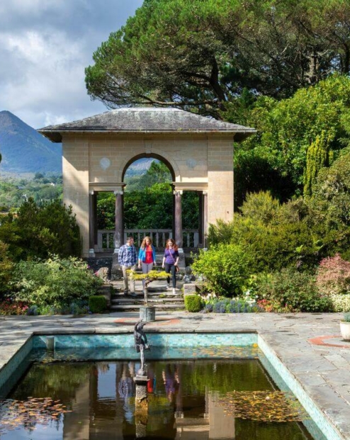 Family strolling in lush garden at Fernhill House Hotel with scenic mountain view.