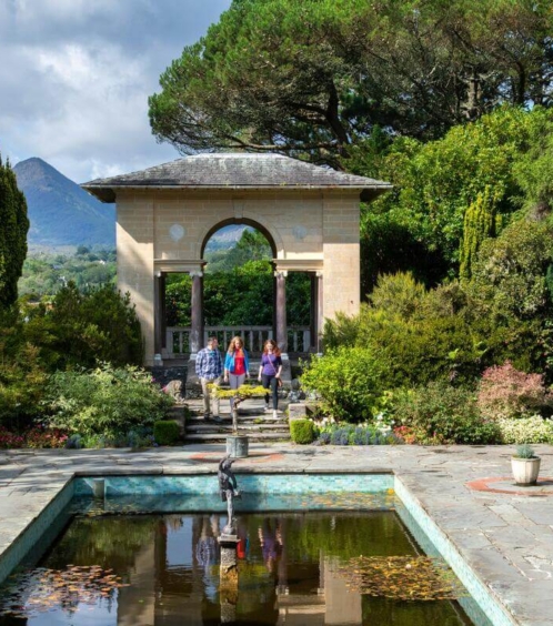 Family strolling in lush garden at Fernhill House Hotel with scenic mountain view.