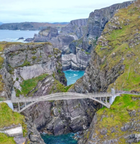 Family enjoying a scenic view from a bridge over a rocky coastal gorge.