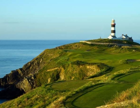 Coastal golf course with a lighthouse overlooking the sea.
