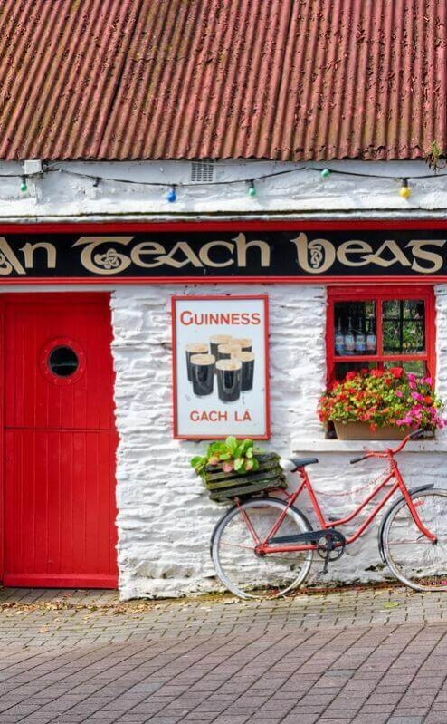 Cosy Irish pub with red door, bikes, and vintage signs, creating a warm, inviting atmosphere.