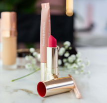 Elegant makeup set with lipstick and flowers on a marble table.