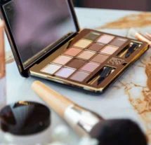 Makeup palette and brushes on marble table in hotel room.