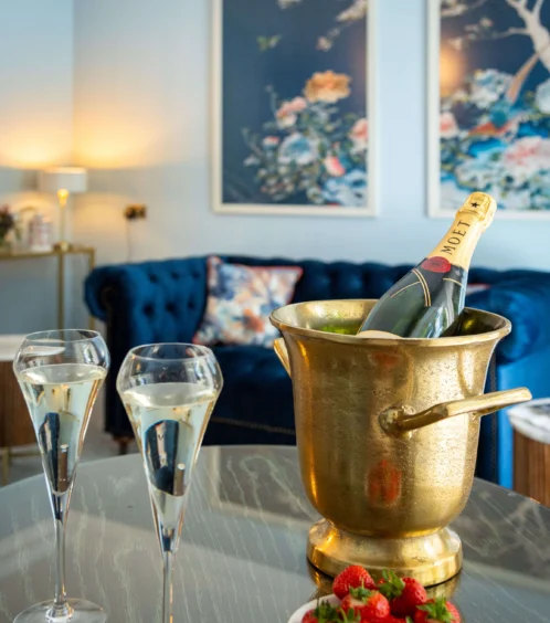 Romantic setting with champagne, strawberries, and elegant sofa at Fernhill House Hotel.