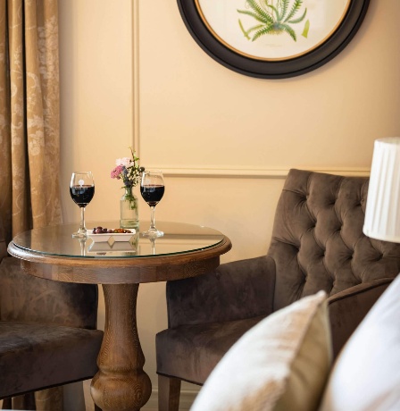 Cosy hotel room with wine glasses on a table and fern artwork on the wall.