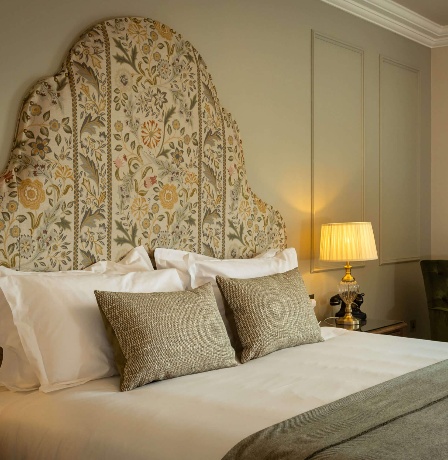 Elegant hotel room with cosy bed, armchair, and a small table set for tea.