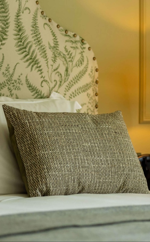 Elegant hotel room with fern-patterned headboard and warm lighting.