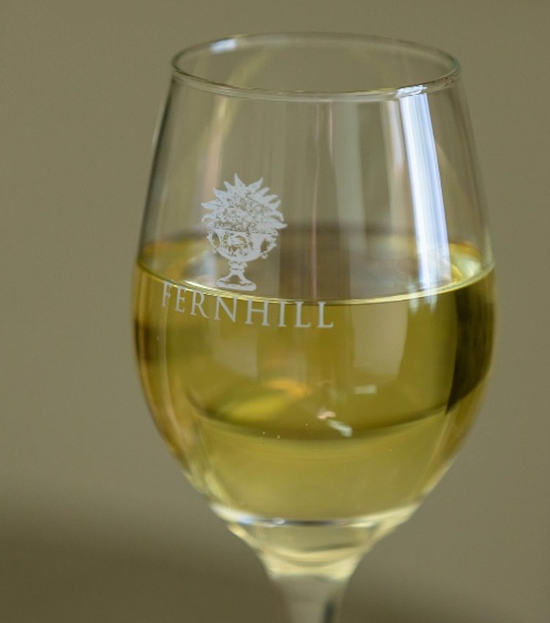 Close-up of a glass of white wine with Fernhill logo, evoking relaxation and luxury at the hotel.