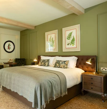 Elegant hotel room with forest view, cosy bed, and seating area.