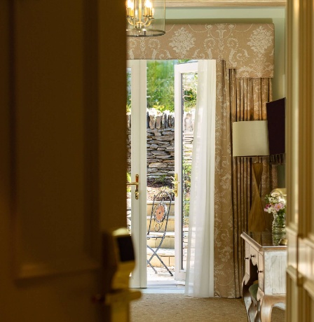Cosy hotel room with garden view and elegant décor, featuring open French doors.
