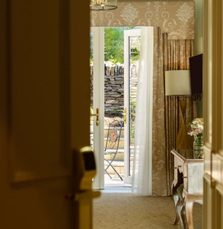 Cosy hotel room with French doors open to a sunny garden patio.