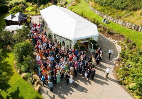 A joyful gathering outside Fernhill House Hotel's marquee with lush greenery.