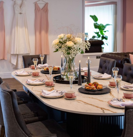 Elegant dining area with flowers and hanging dresses at Fernhill House Hotel.