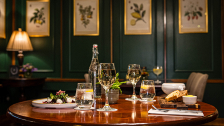 Elegant dining setup in cosy hotel restaurant with glasses of wine on a wooden table.
