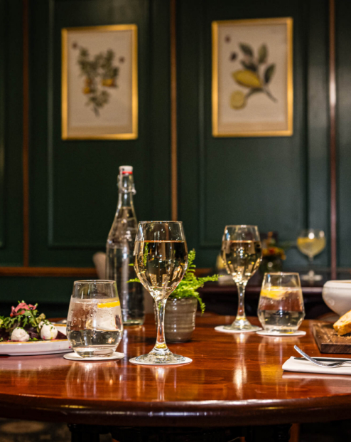 Elegant dining setup in cosy hotel restaurant with glasses of wine on a wooden table.