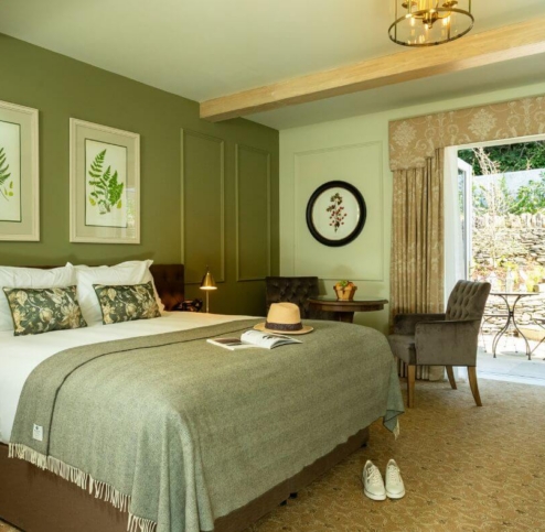 Cosy hotel room with double bed, open patio doors, and garden view.