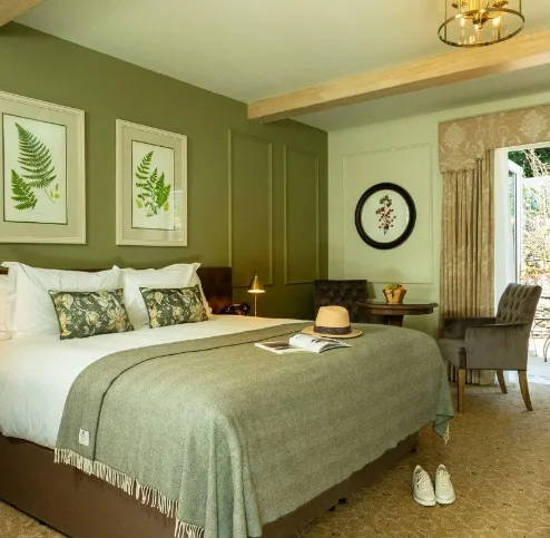 Elegant hotel room with king-size bed, open patio doors, and cosy seating area.