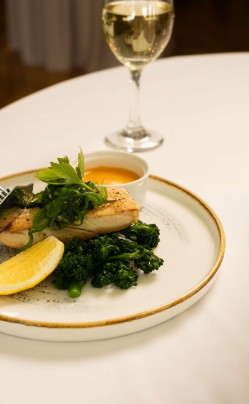 Elegant dining with fish, greens, and wine at Fernhill House Hotel.