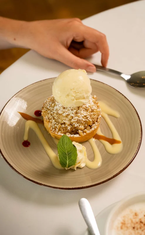 Guest enjoys apple crumble dessert with ice cream at Fernhill House Hotel restaurant.