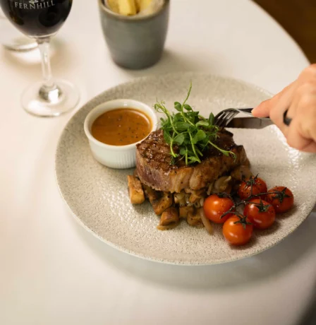 Elegant dining with steak, chips, and wine at Fernhill House Hotel.