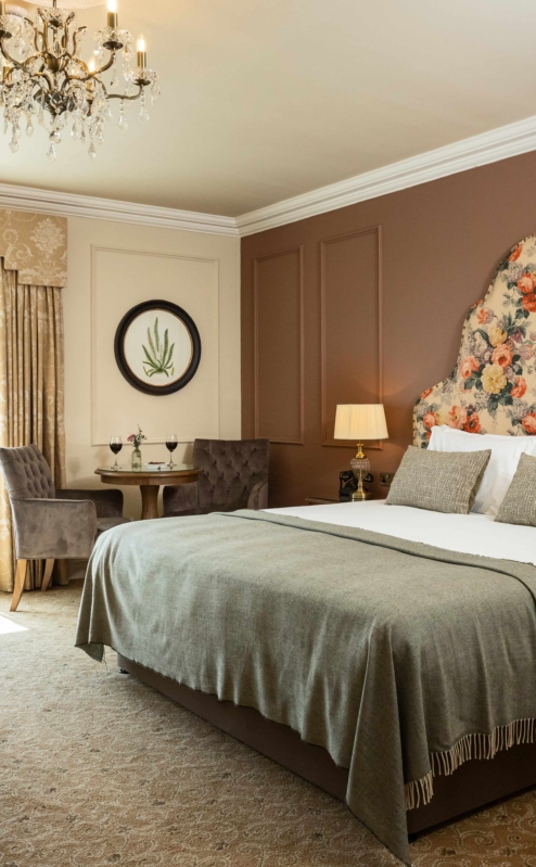 Elegant hotel room with a cosy bed, seating area, and countryside view.