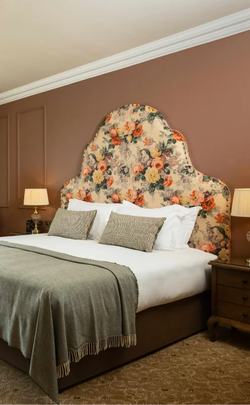Elegant hotel room with countryside view, featuring a plush bed and cosy seating area.