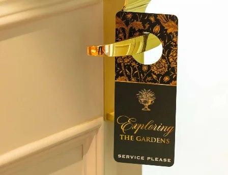 Gold door handle with "Exploring the Gardens" sign in a hotel room hallway.