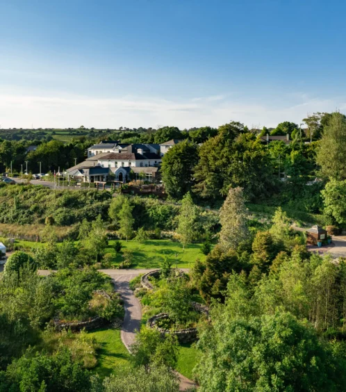 Family enjoying stroll in lush Fernhill House Hotel gardens on a sunny day.