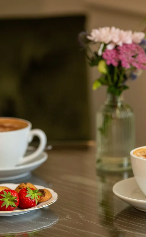 Cosy tea time with lattes and biscuits at Fernhill House Hotel lounge.
