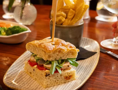 Family dining at Fernhill House Hotel with gourmet sandwich and chips on a wooden table.