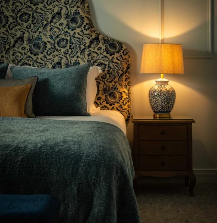 Cosy hotel room with elegant lamp and floral headboard at Fernhill House Hotel.